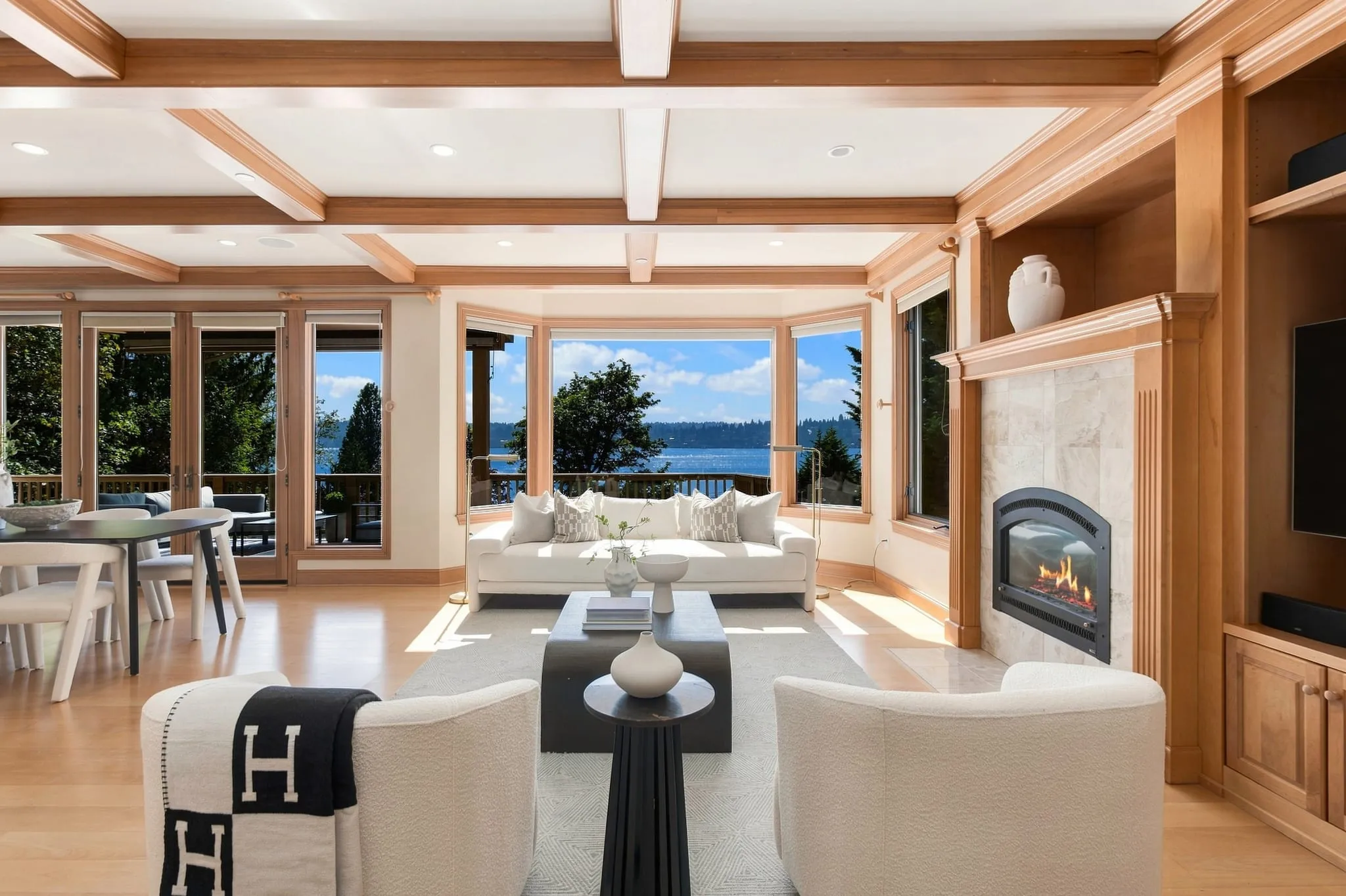 Living room with a wood coffered ceiling, fireplace and bay windows onto the lake