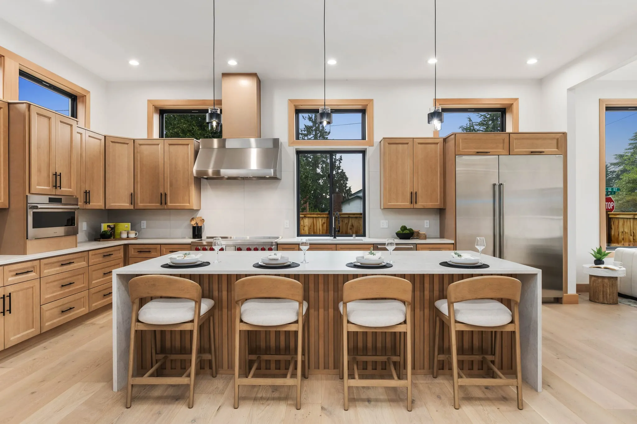 Kitchen with warm wood cabinetry, a waterfall island and four stools, photographed by ACRE Seattle